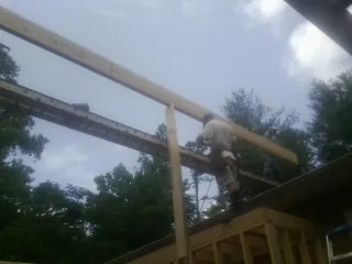 Carpenter setting a ridge beam over a new addition frame — Ice Dam Removal by Roofing Brothers in Davenport