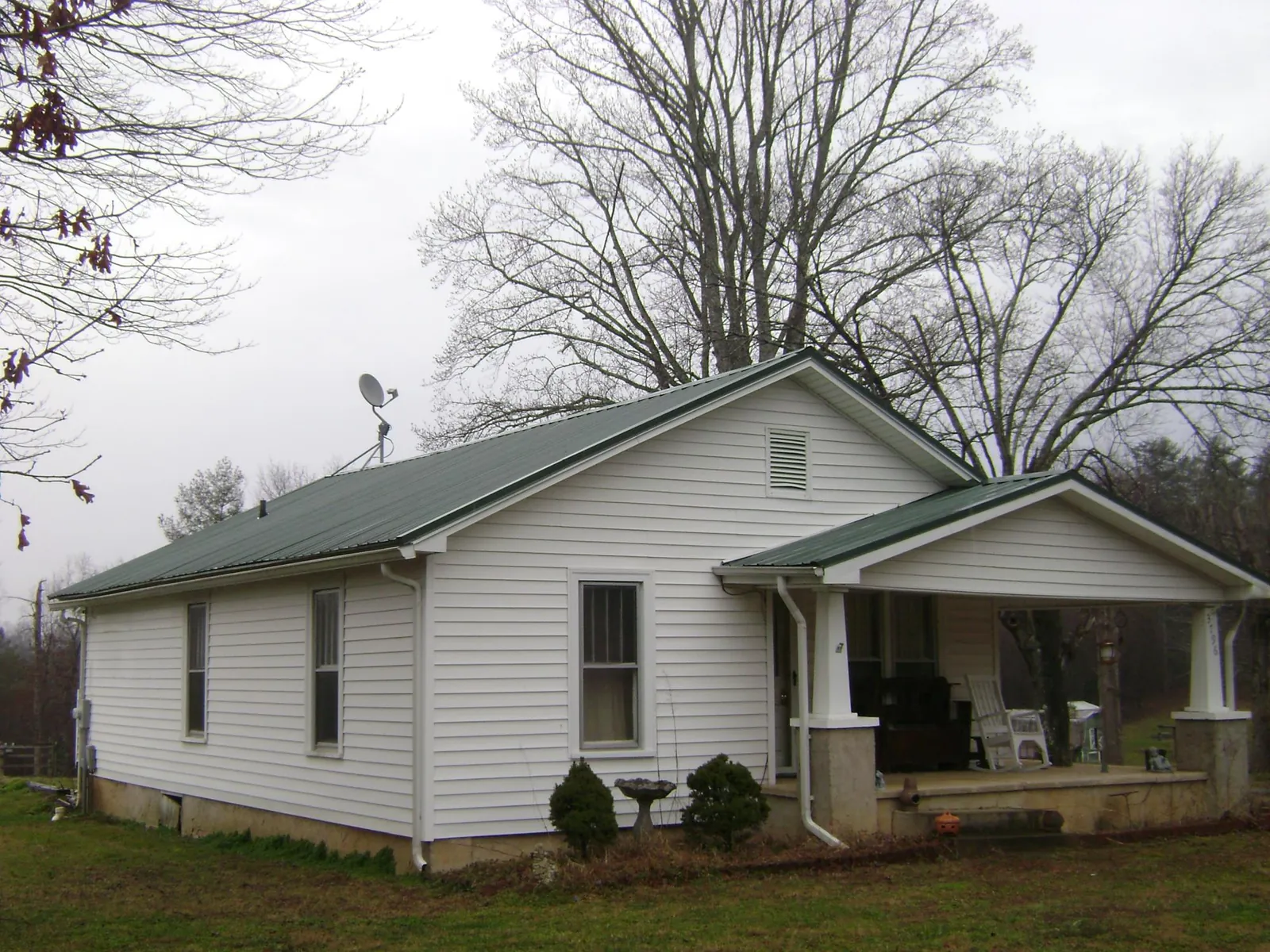 Green metal roof on a white bungalow with a side porch in Davenport